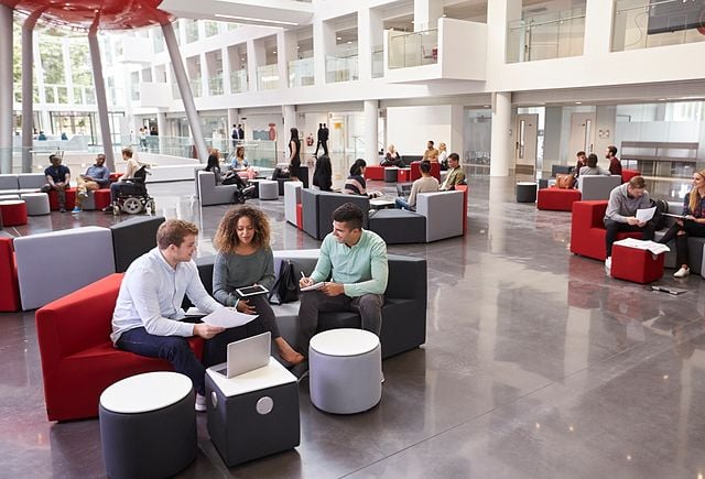 Students sitting in university atrium, three in foreground